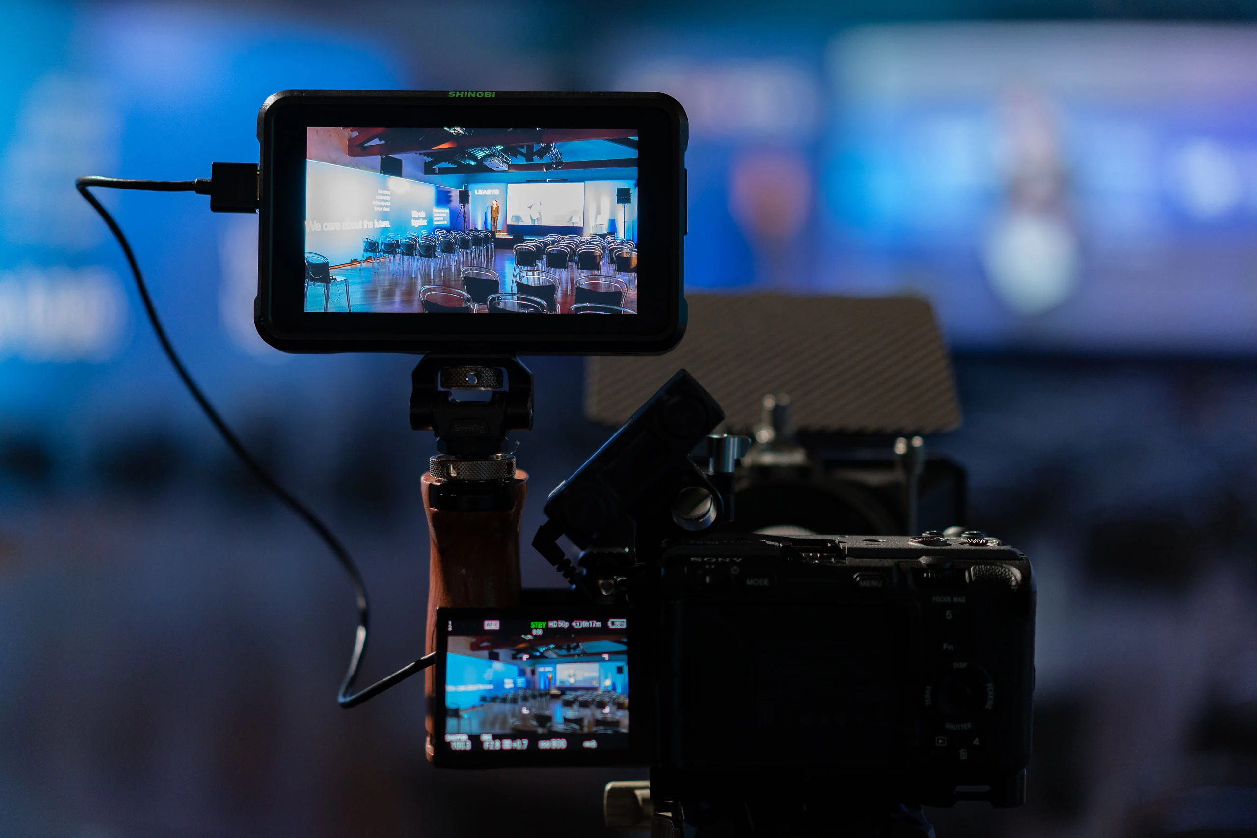 Videocamera con monitor che inquadra una sala allestita per una conferenza